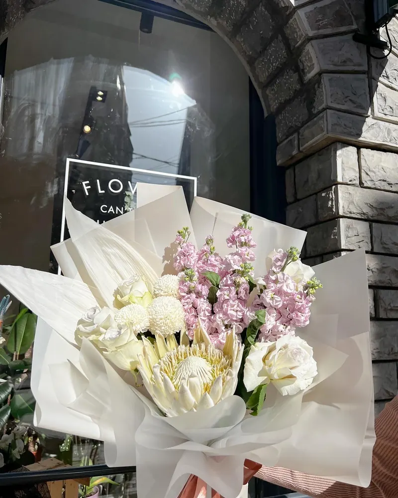 White and lilac bouquet with stock flowers, wrapped in white paper